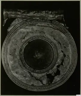 Gold round object from Lapithos Kastros tombs, seen from above, with a twisted-cord border and central boss.
