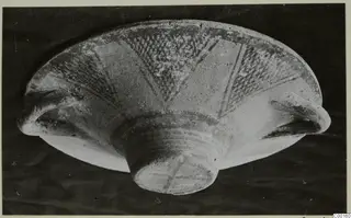 White Painted I bowl from Lapithos, photographed at an angle with dark painted hatched bands on its pale surface