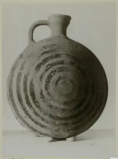 White Painted I jug with a strap handle and dark concentric circles painted on its round body