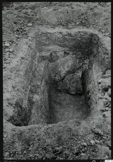 Excavated tomb chamber at Vrysi tou Barba, Lapithos, with a large stone block against the back wall during excavation.