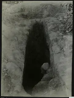 Tomb 408 at Lapithos Kastros during excavation, a deep narrow shaft cut into the earth with stones inside.