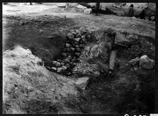 Excavation trench at the theatre at Soli, with a stone wall on the left and a cylindrical stone piece in the cut.