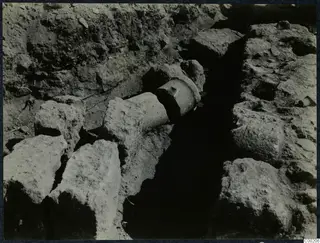 Excavation trench at Soli with large stone blocks on either side and a cylindrical stone piece lying across it