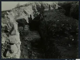 Excavation trench at Soli theatre with large stone blocks in the left wall and a tree at the top left