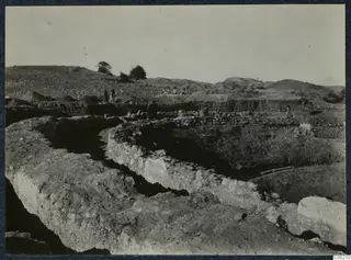 Excavation of the theatre at Soli, with exposed stone walls and figures working in the trenches.