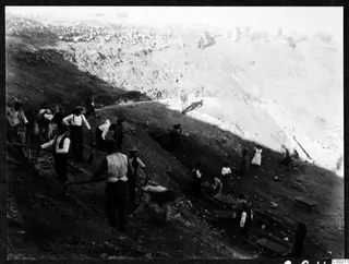 Workers digging the slope at the theatre at Soli, with picks, shovels and wheelbarrows in a steep cutting