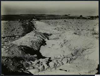 Excavation trench at Soli with stones along its floor and a group of people standing on the far rim