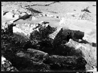 Excavated stone walls and rubble at the theatre at Soli, with two people standing among the ruins.