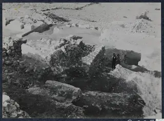 Excavated stone walls at the theatre at Soli, with two people standing among the ruins.