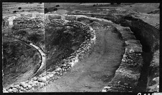 The theatre at Soli during excavation, with curved stone walls, a cleared trench and scattered trees beyond