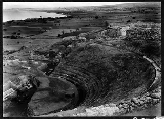 The theatre at Soli during excavation, with curved tiers of stone seating exposed above the bay and fields.