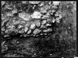 Close view of irregular stones packed together in dark excavated soil at Soli theatre