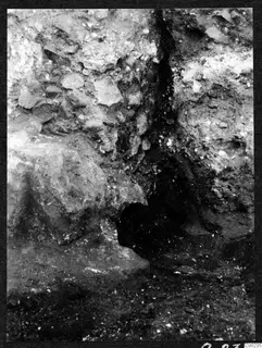Excavation at Soli showing rough stones in a cutting wall beside a dark hollow in the soil
