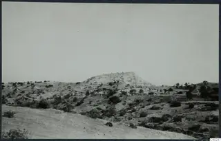Landscape at Vouni with a flat-topped hill rising above scrub and scattered trees, with open slopes in the foreground.