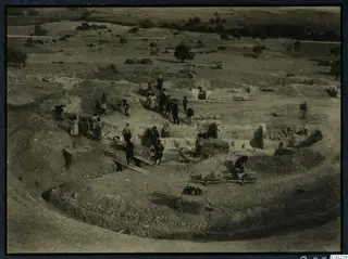Elevated view of workers excavating the theatre at Soli, with wheelbarrows on planks and exposed stone walls