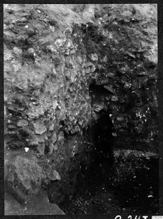 Excavated stone wall at Soli theatre, with a dark recess opening between packed stones