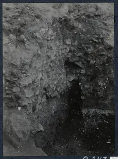 Excavated rubble-stone wall at the theatre at Soli, with a narrow dark opening at centre right.