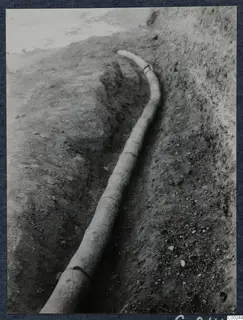 Long curved pipe lying in an excavation trench at Soli, with earth banks on either side.