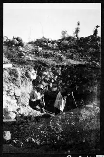 Excavation at the theatre at Soli, with two workers in a trench beside a stone wall.