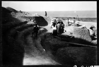 Excavation at Soli theatre with workers, wheelbarrows and cut stones, the sea beyond.