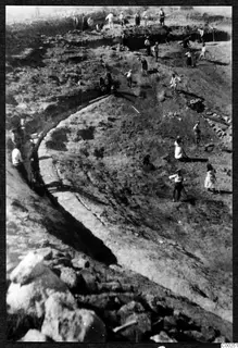 Excavation of the theatre at Soli, with workers digging across the slope and a curved stone edge running through the site