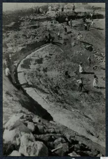Excavation at the theatre at Soli, with workers digging a curved trench beside exposed stonework.