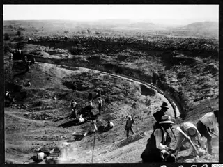 Excavation of the theatre at Soli, with workers digging in a curved cutting and a stone wall on the ridge above