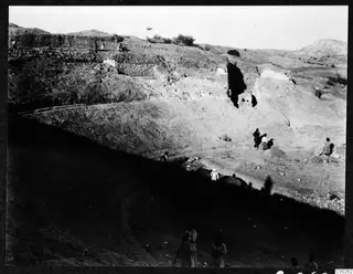Excavation at the theatre at Soli, with stone walls, spoil heaps and people working on the excavated ground.
