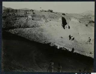 Excavation at the theatre at Soli, with stone walls along the cutting and people working among the earth and stones.