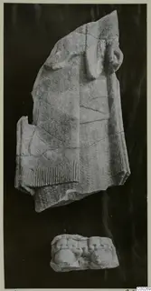 Limestone sculpture fragment of a figure in a fringed garment, with a smaller carved piece below, from Vouni