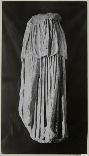 Half of a draped marble sculpture, photographed against a dark background.