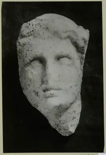 Marble head sculpture from Soli, shown frontally against a dark background