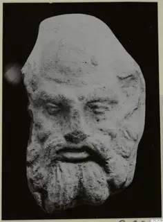 Small terracotta head of a bearded man from Soli, shown frontally against a black background