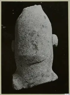 Terracotta fragment of a figure with a broken top and two side projections, photographed alone on a dark background