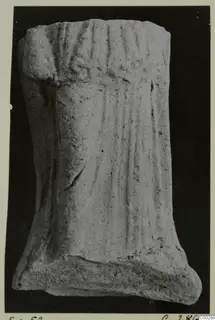 Fragment of a small figure with vertical folds, found at Soli, photographed against a black background