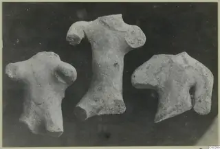 Three terracotta figurine fragments, torsos without heads or limbs, set against a dark background.