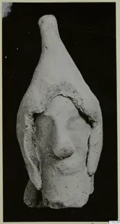 Terracotta Minor Plastic 3, a small terracotta figurine of a head with a tall tapering top, from Soli, against a black background.