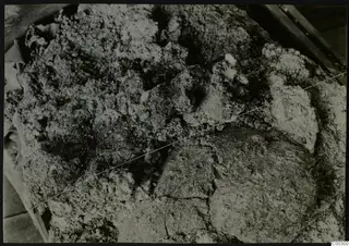 Close view of soil-encrusted objects in Tomb 322 b at Lapithos, with a taut wire stretched diagonally across them