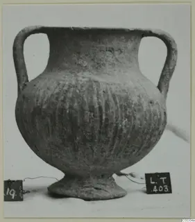 Black-slipped pottery jug with two handles, ribbed body and a ring foot, shown against a plain background