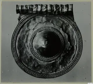 Round gold-coloured pendant disc with twisted-wire borders, a raised central boss and a ribbed loop along the top edge.