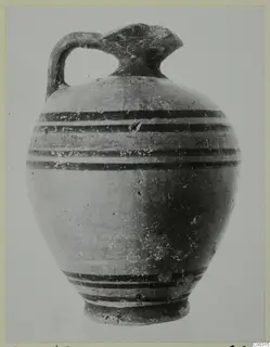 Pottery juglet with a single strap handle, a trefoil-like spout and horizontal dark bands painted around the body.