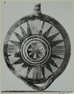 Round pottery vessel with a nozzle-like projection and loop handle, painted with dark radiating wedges and concentric rings
