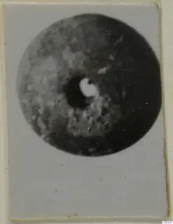 Blurred photograph of a round stone disc with a central hole, from Lapithos Tomb 403