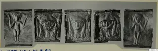 Five embossed metal plaques in a row: two with standing figures with raised arms, three with frontal faces wearing headdresses.