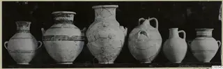 Six pottery vessels from Tomb 403 at Lapithos, standing in a row against a dark background