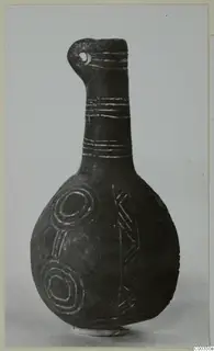 Black polished vessel with a long neck, a pierced lug at the rim, and incised bands, concentric circles and chevrons on the body