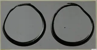 Two open gold rings from the Kastros tombs at Lapithos, photographed side by side on a grey background.