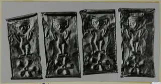 Four thin embossed metal plates in a row, each showing a standing figure with raised arms above a rosette motif.