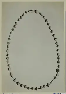 Necklace of about fifty small beads strung on cord and laid out in an oval loop from Lapithos