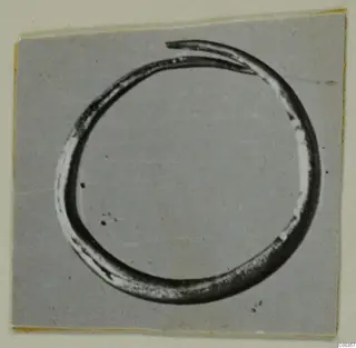Gold ring from Lapithos, a thin open hoop with one end overlapping the other, photographed on a grey card mount